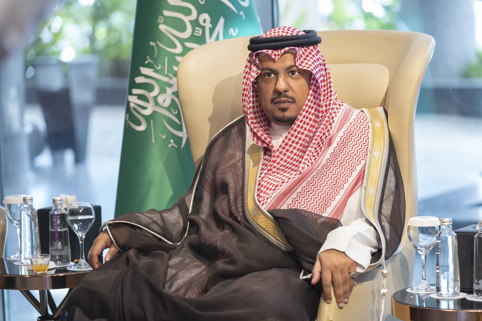 A senior official seated before the Saudi national flag