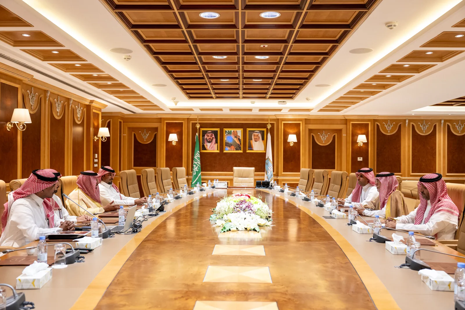 A bilateral delegation seated in a palatial state conference hall beneath the Saudi flag