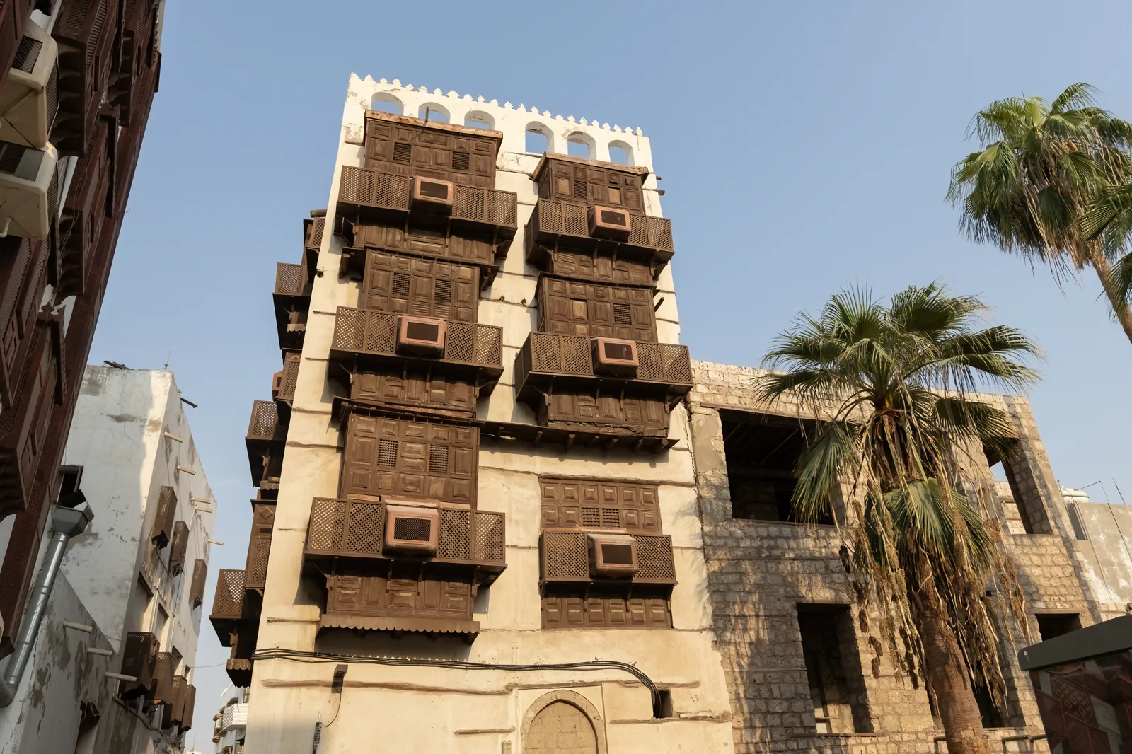 Full facade of multi-storey Al-Balad mashrabiya tower with palm, Jeddah