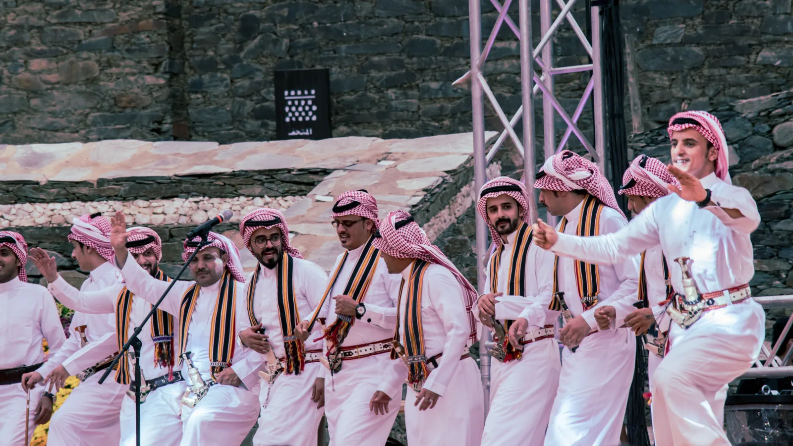 Saudi men in thobes performing the Ardha folk sword dance on an outdoor stage