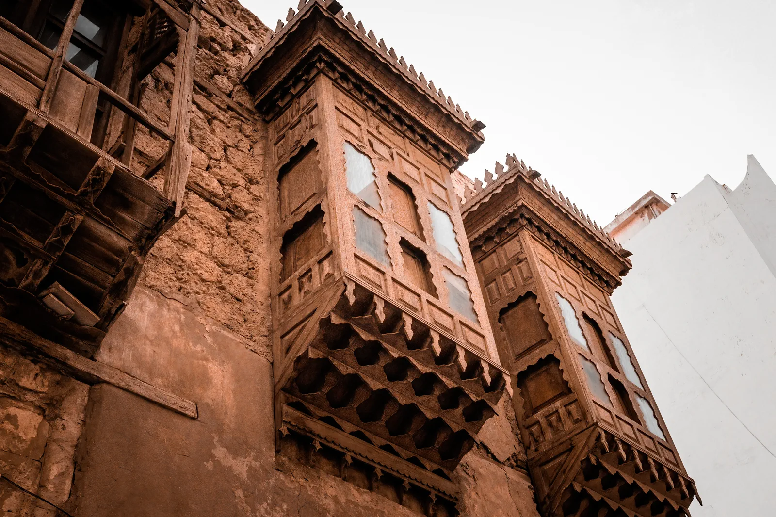 Close-up of two ornate carved wooden balconies on coral-stone facade, Jeddah