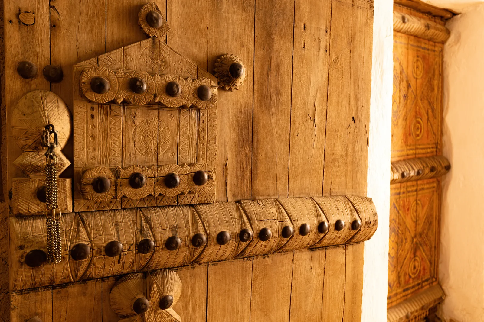 Warm-lit carved wooden door with studded beam, Al-Masmak Palace Riyadh