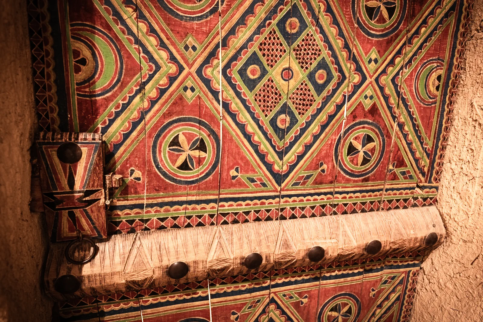 Vividly painted geometric carved door in red green blue, Najd folk tradition