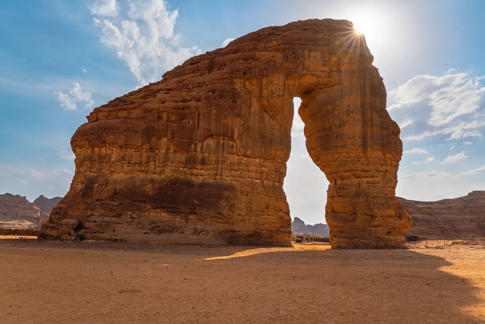Jabal AlFil Elephant Rock natural arch with sunburst, AlUla desert