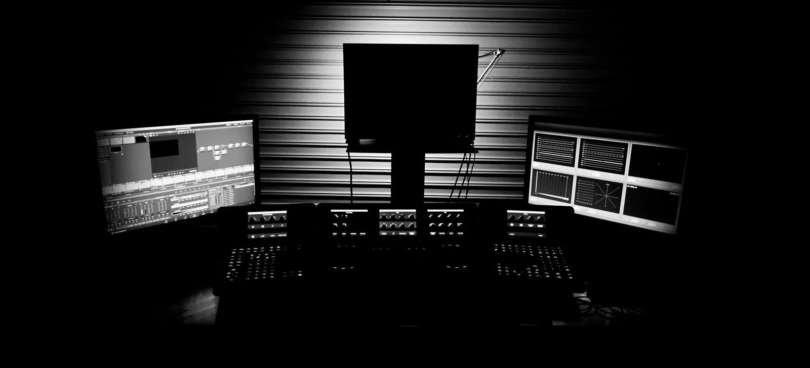 Professional video editing suite with three monitors and a colour-grading panel