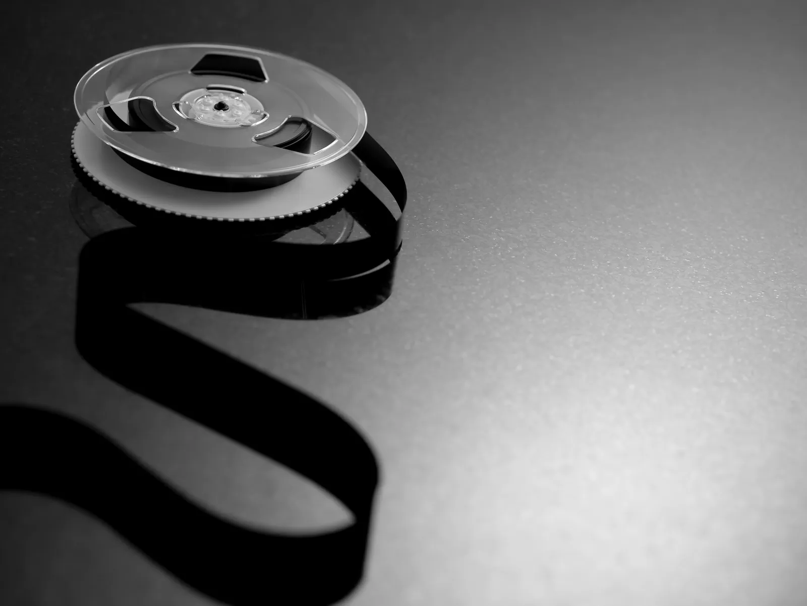 Vintage film reel unspooling on a dark surface
